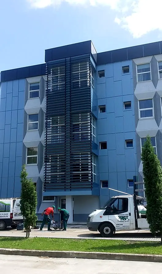 Clădire de birouri placată cu bond albastru, cu parasolare din lamele de aluminiu pe casa scării