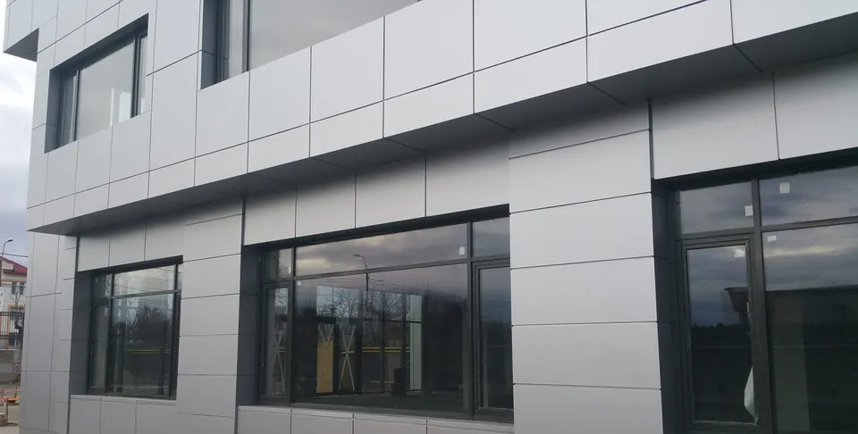 Fațadă ventilată cu casete din bond gri deschis și ferestre din aluminiu