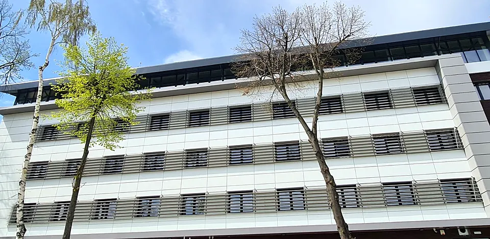 Fațadă lungă placată cu bond alb, cu parasolare din lamele orizontale de aluminiu pe toată lungimea fiecărui etaj