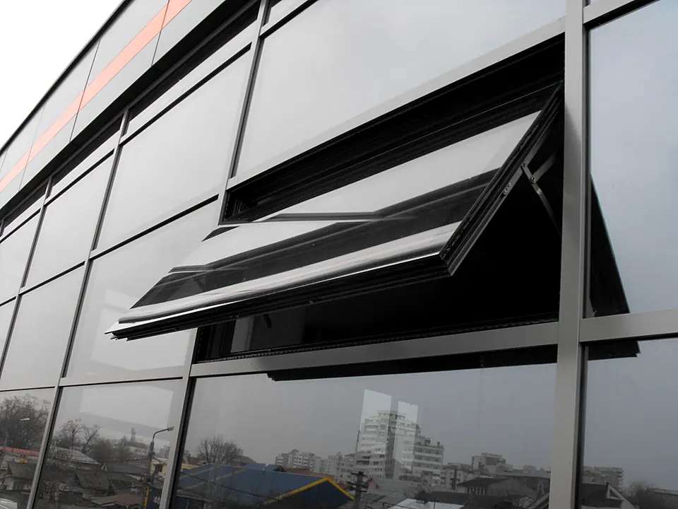 Fereastră cu deschidere în proiecție integrată într-un perete cortină din aluminiu gri