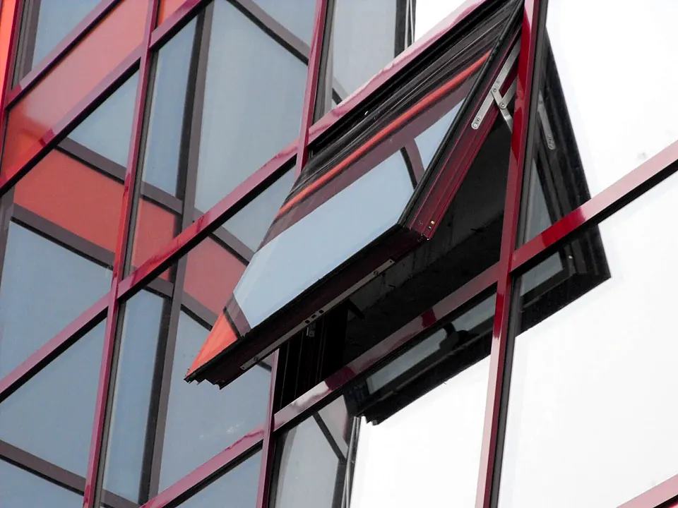 Detaliu de fereastră deschisă în proiecție pe un perete cortină cu profile din aluminiu roșu