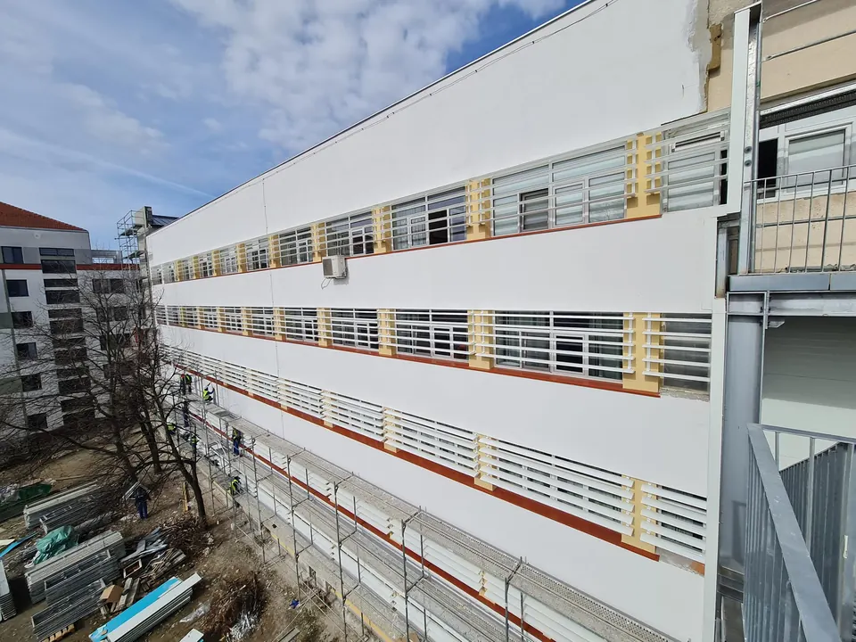 Fațadă lungă de clădire publică echipată cu parasolare din aluminiu la fiecare etaj