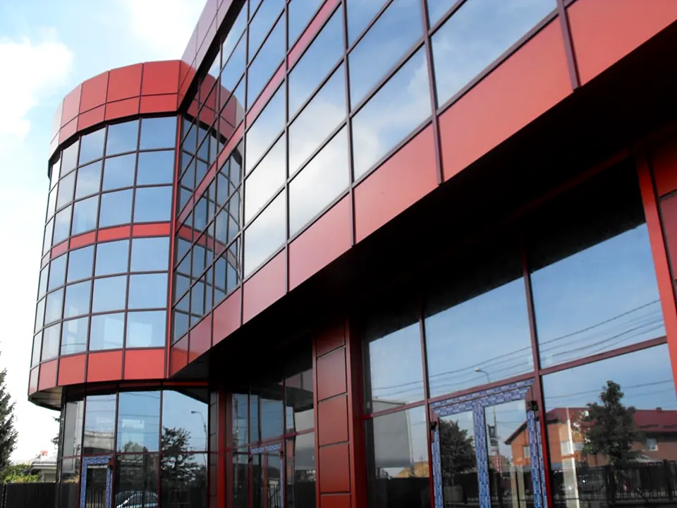 Corp rotunjit din perete cortină cu casete din bond roșu și vitrine mari la parter