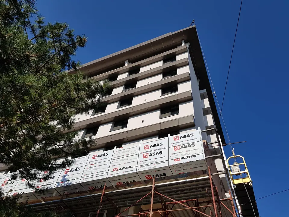 Placare cu bond pe fațada unui bloc de locuințe, executată de pe platformă suspendată