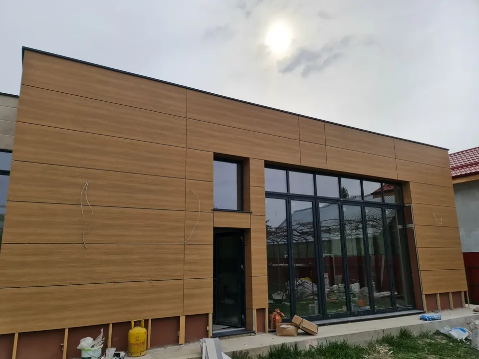 Clădire nouă placată cu panouri HPL cu efect de lemn și tâmplărie din aluminiu antracit